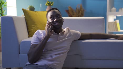 African-young-man-talking-on-the-phone-alone-at-night-at-home.
